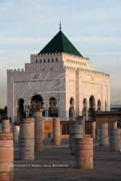 Image du Maroc Professionnelle de  Le tombeau du plus populaire des sultans du Maroc, Mohammed V, père de l’indépendance repose ici dans cette  demeure bâtie en marbre blanc et couronnée par un toit pyramidale orna de tuiles vertes, symbole de la royauté. Sa construction a nécessita une dizaine d’année, au premier plan  les colonnes de l’esplanade de la Mosquée Hassan à Rabat, Jeudi 1er Mars 2007. (Photo / Abdeljalil Bounhar)
